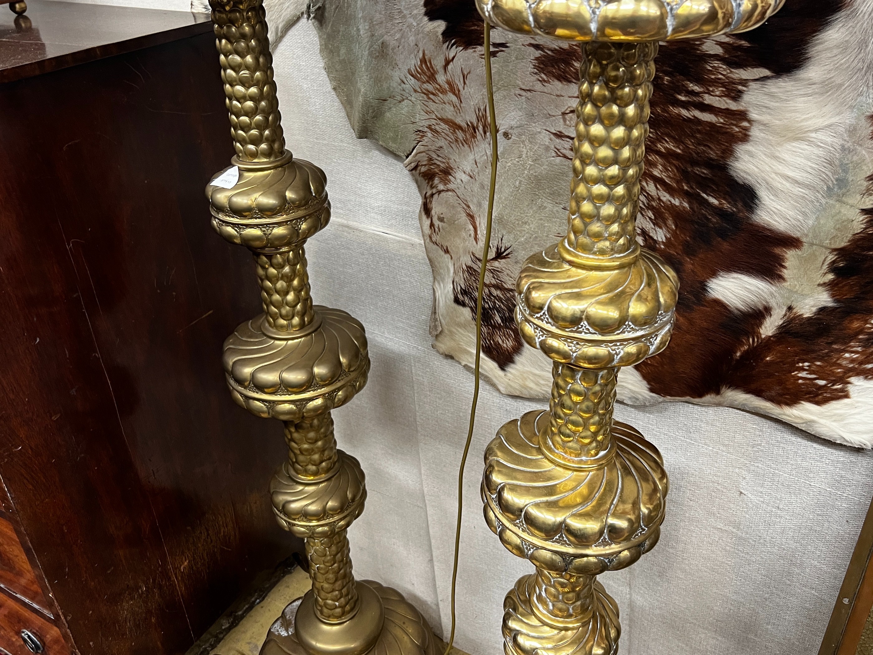 A pair of large Dutch embossed brass altar sticks converted to electricity, height 150cm